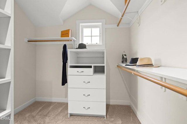 walk in closet with vaulted ceiling and light carpet