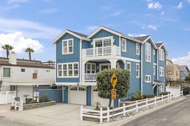 view of front facade with a balcony, driveway, board and batten siding, an attached garage, and fence