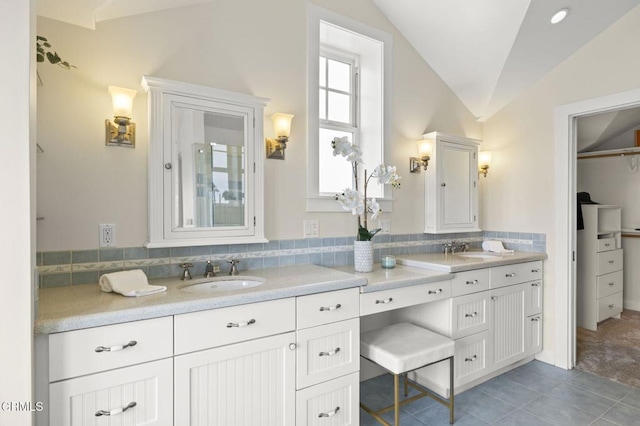 bathroom with double vanity, a sink, and lofted ceiling