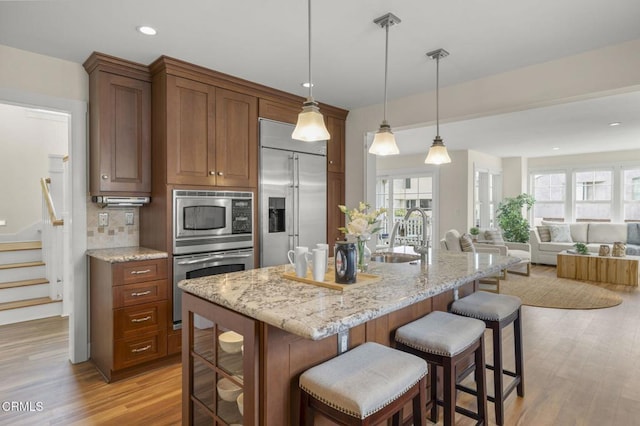 kitchen featuring a kitchen breakfast bar, built in appliances, a healthy amount of sunlight, and a sink