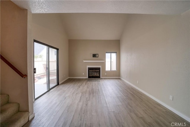 10710 El Camino Real Unit 26, Atascadero, CA 93422 - unfurnished living room with a fireplace with flush hearth, stairway, vaulted ceiling, baseboards, and wood finished floors