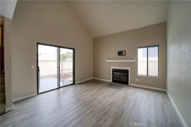 10710 El Camino Real Unit 26, Atascadero, CA 93422 - unfurnished living room featuring wood finished floors, a healthy amount of sunlight, a glass covered fireplace, and high vaulted ceiling