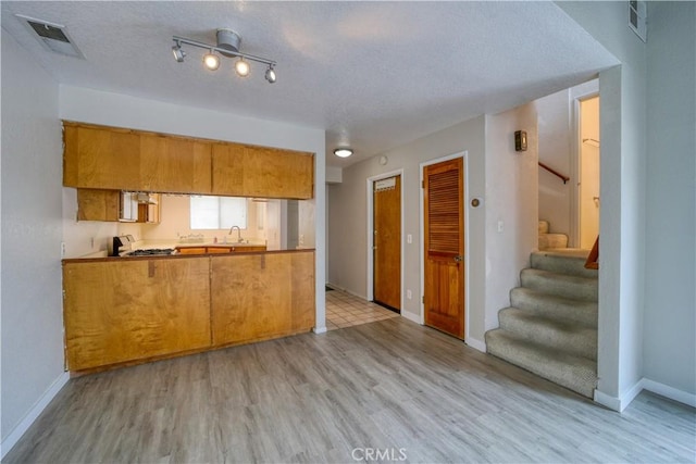 10710 El Camino Real Unit 26, Atascadero, CA 93422 - kitchen with baseboards, visible vents, light wood-style flooring, and brown cabinetry