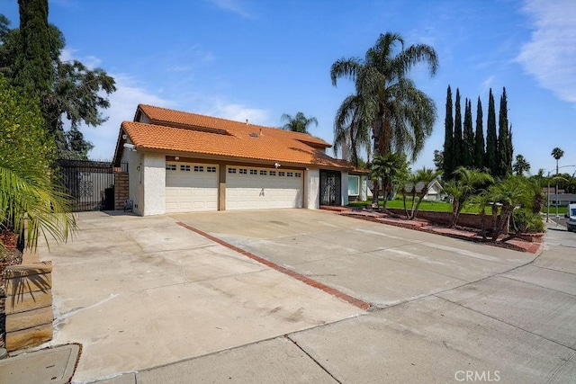 2161 Stonefield Pl, Riverside, CA 92506 - view of front facade with an attached garage, stucco siding, driveway, and a tile roof
