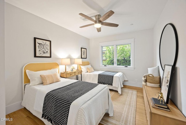 bedroom with a ceiling fan, baseboards, and light wood-type flooring