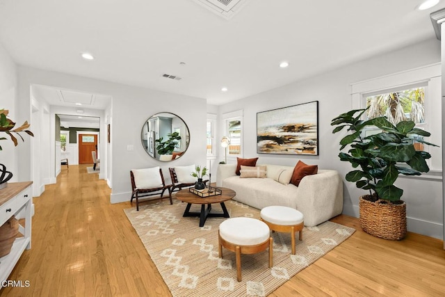 living room with visible vents, a healthy amount of sunlight, attic access, and light wood-style floors