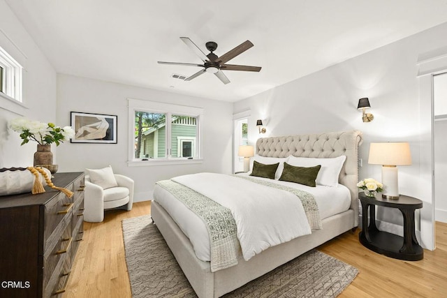 bedroom featuring a ceiling fan, baseboards, visible vents, and light wood-style flooring