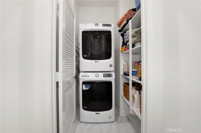 clothes washing area featuring stacked washer and clothes dryer, laundry area, and marble finish floor