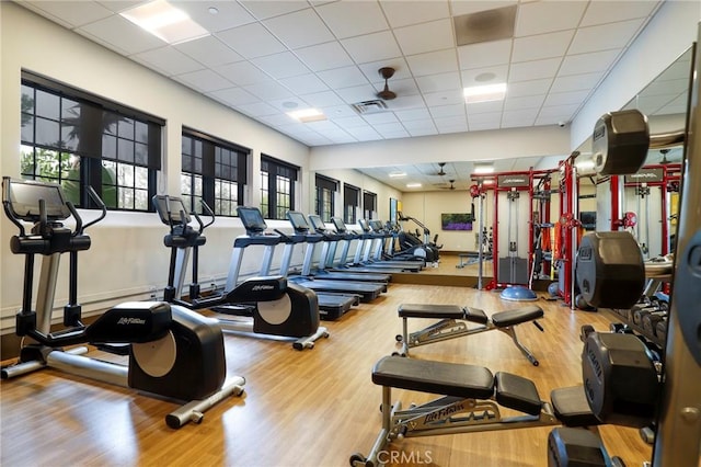 gym with wood finished floors, a drop ceiling, and visible vents