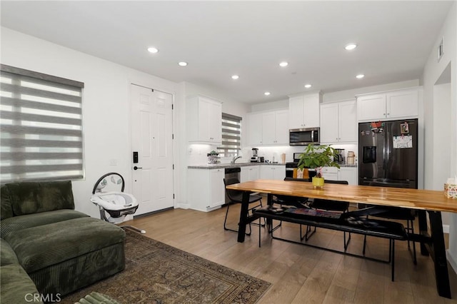 interior space with white cabinetry, appliances with stainless steel finishes, light countertops, recessed lighting, and wood finished floors
