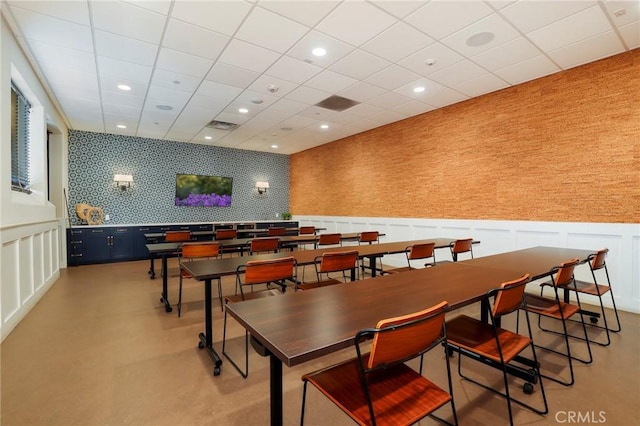 dining space with a wainscoted wall, wallpapered walls, and a decorative wall