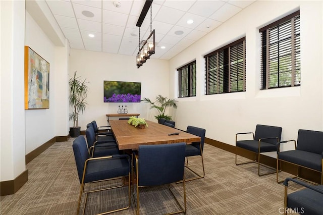 carpeted dining area with baseboards, a paneled ceiling, and plenty of natural light