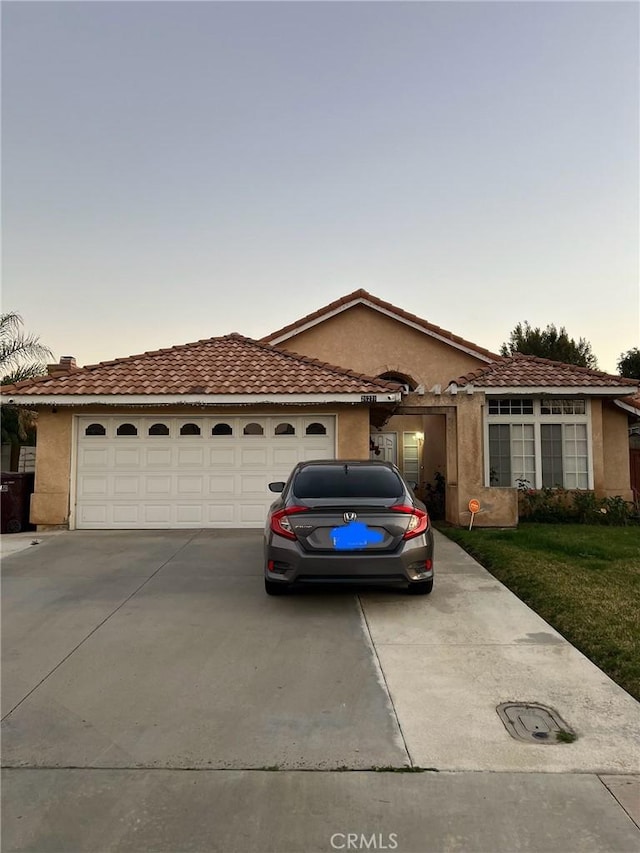view of front of home featuring stucco siding, concrete driveway, and an attached garage