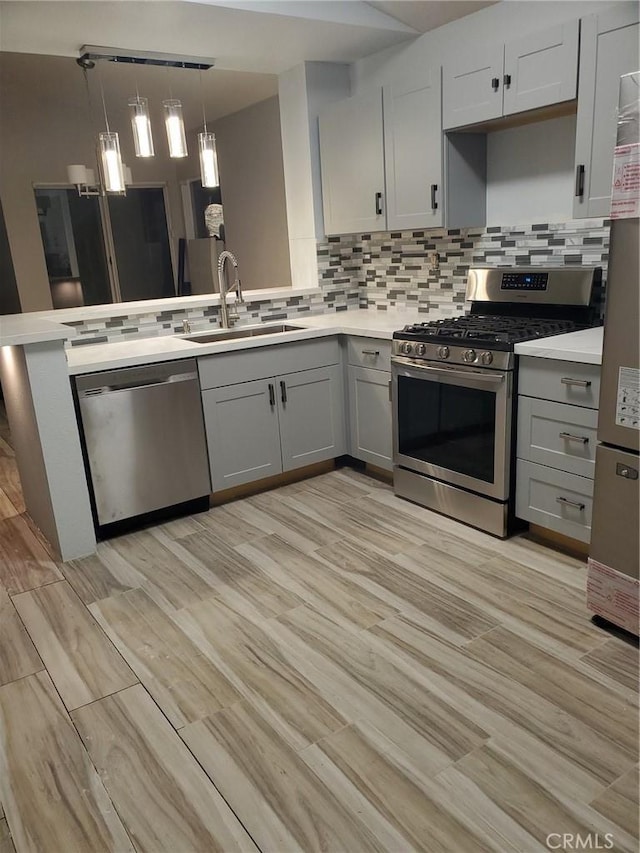 kitchen with tasteful backsplash, a sink, gray cabinetry, stainless steel appliances, and light countertops