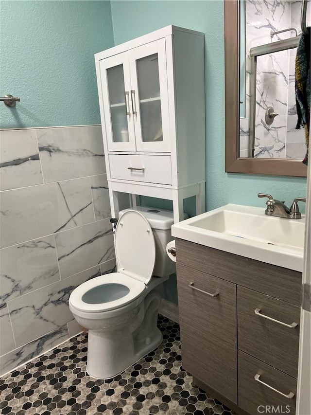 bathroom with a textured wall, vanity, toilet, and a shower stall