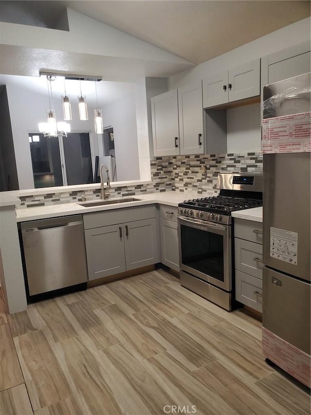 kitchen with stainless steel appliances, light wood-style floors, backsplash, a sink, and gray cabinetry