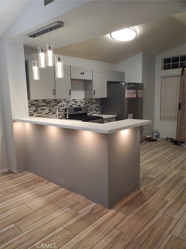 kitchen with stainless steel appliances, light wood-style floors, backsplash, a peninsula, and light countertops
