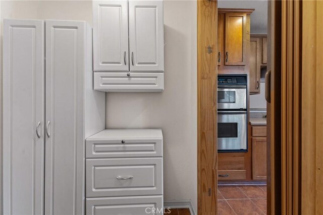 interior space featuring dark tile patterned flooring, light countertops, white cabinets, and stainless steel double oven