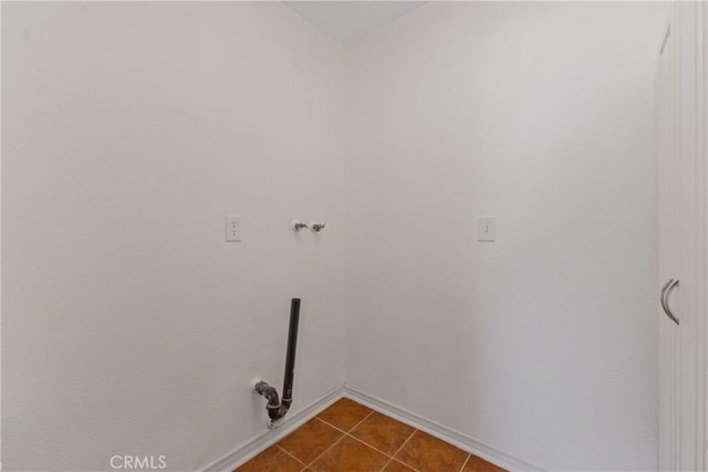 laundry room with laundry area, baseboards, and dark tile patterned floors