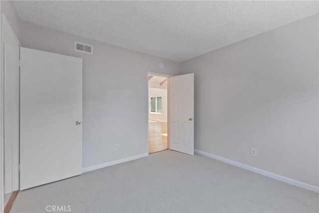 unfurnished bedroom featuring visible vents, a textured ceiling, carpet, and baseboards