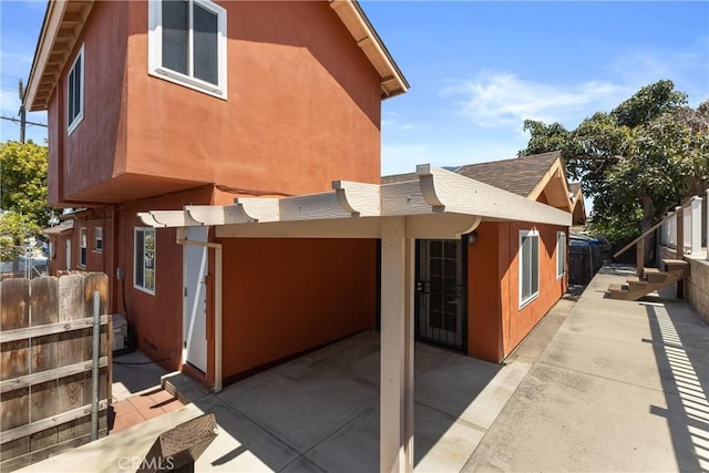 rear view of house with a patio area, stucco siding, and fence
