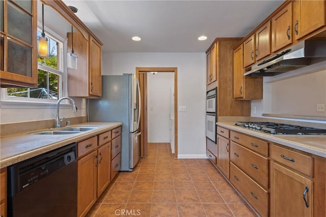kitchen with a sink, appliances with stainless steel finishes, brown cabinetry, and under cabinet range hood