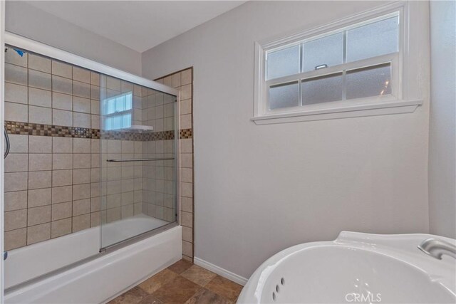 full bathroom featuring a sink, baseboards, and shower / bath combination with glass door