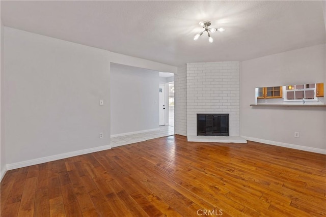 unfurnished living room with baseboards, a fireplace, and hardwood / wood-style flooring