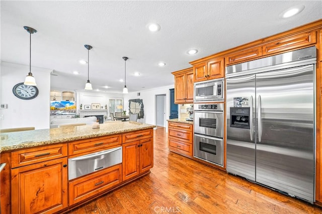 kitchen featuring recessed lighting, dark wood-style flooring, built in appliances, brown cabinetry, and a warming drawer