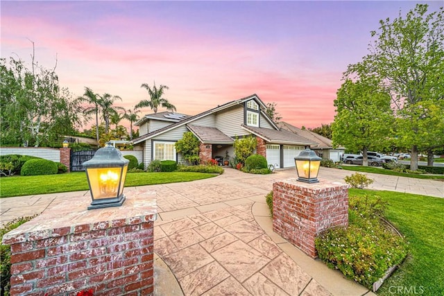 view of front of property with a lawn, driveway, brick siding, an attached garage, and fence