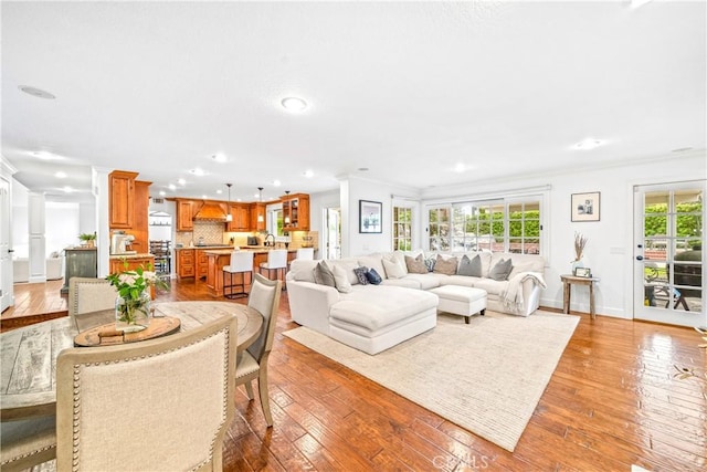 living room featuring ornamental molding, recessed lighting, light wood-style flooring, and baseboards