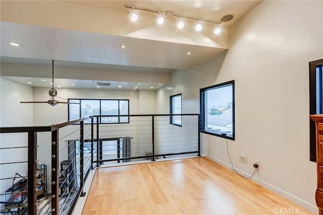 unfurnished room with track lighting, wood finished floors, recessed lighting, and baseboards
