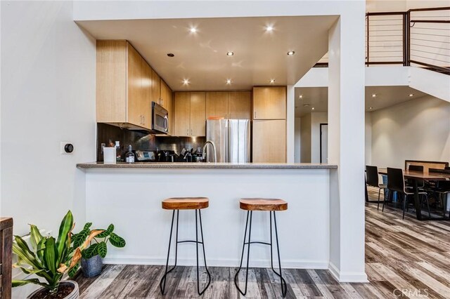 kitchen featuring recessed lighting, a sink, stainless steel appliances, tasteful backsplash, and wood finished floors