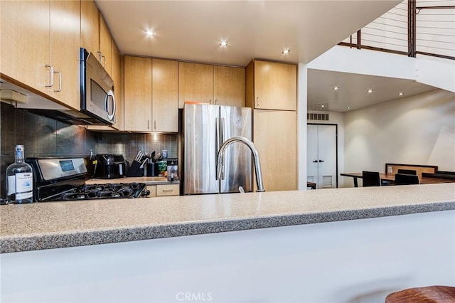 kitchen with stainless steel appliances, decorative backsplash, recessed lighting, and light countertops