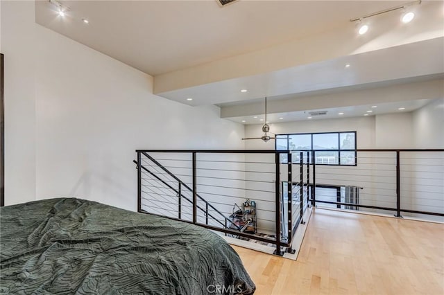 bedroom with recessed lighting, wood finished floors, and rail lighting