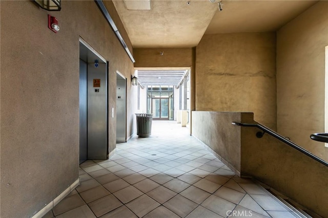 hall with light tile patterned floors and elevator