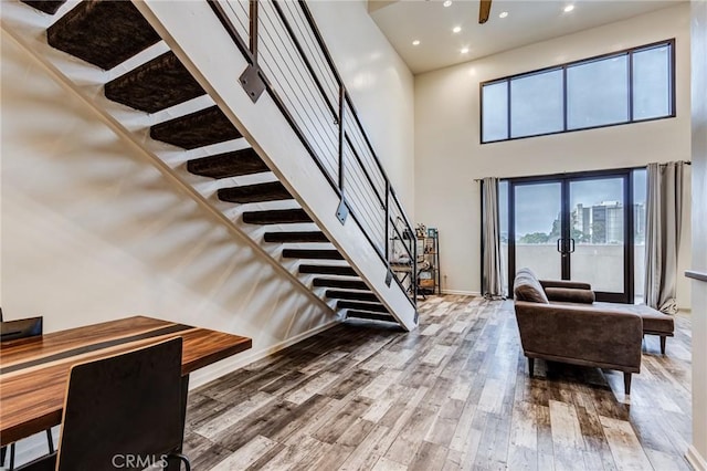 foyer entrance featuring recessed lighting, wood finished floors, stairs, baseboards, and a towering ceiling