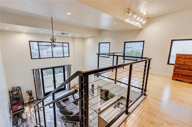 hall with an upstairs landing, baseboards, recessed lighting, a towering ceiling, and wood finished floors