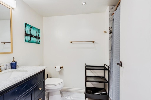 bathroom with vanity, curtained shower, toilet, baseboards, and wood finished floors