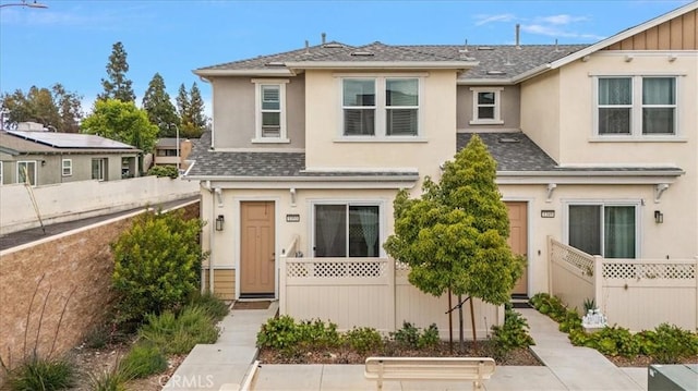 townhome / multi-family property featuring stucco siding, a shingled roof, and fence