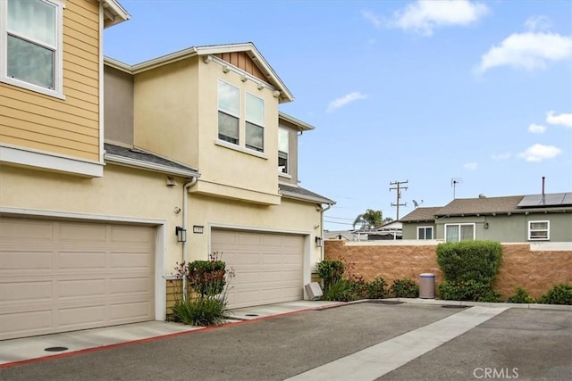 exterior space featuring a garage, stucco siding, and fence