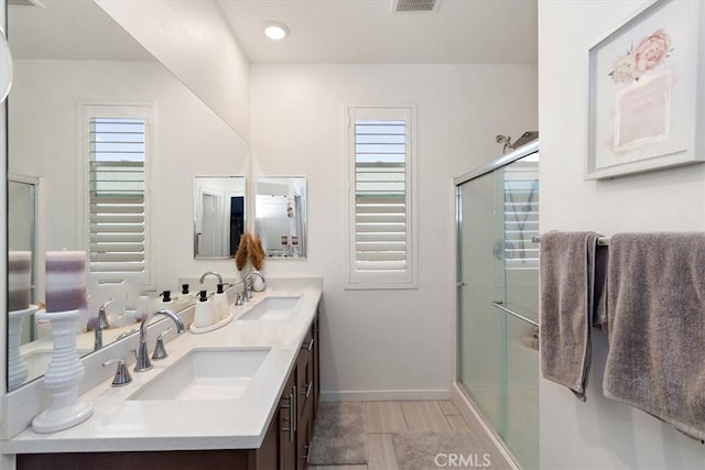 full bath with double vanity, baseboards, a sink, and a stall shower