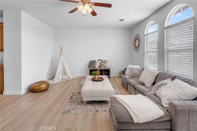 living room with baseboards, ceiling fan, visible vents, and light wood-style flooring