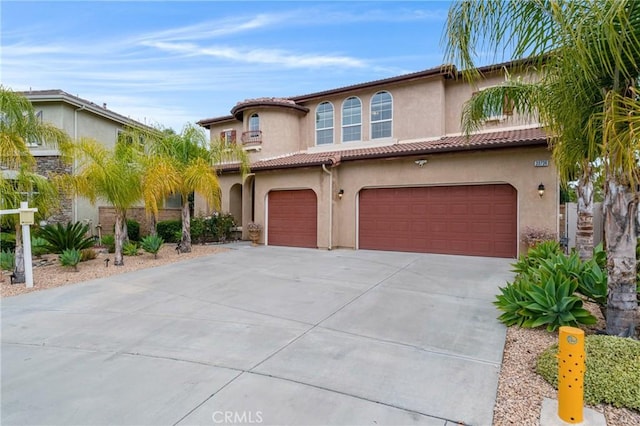 mediterranean / spanish house featuring a garage, driveway, a tile roof, and stucco siding