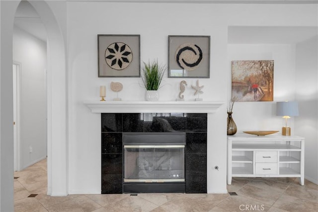 details featuring arched walkways, baseboards, and a tile fireplace