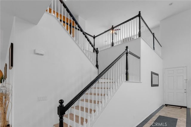 stairs featuring baseboards and a towering ceiling