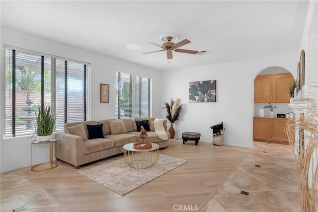 living room with visible vents, arched walkways, and ceiling fan