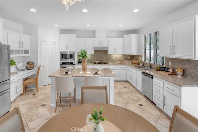 kitchen with backsplash, a center island, a sink, white cabinets, and stainless steel appliances