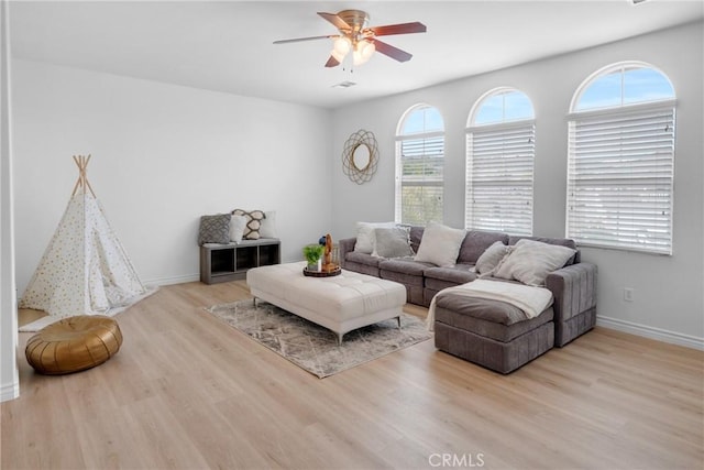 living room featuring a ceiling fan, baseboards, and wood finished floors