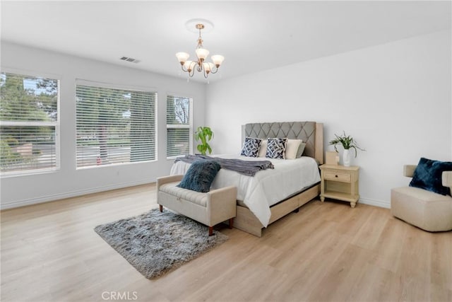 bedroom with baseboards, light wood finished floors, a notable chandelier, and visible vents